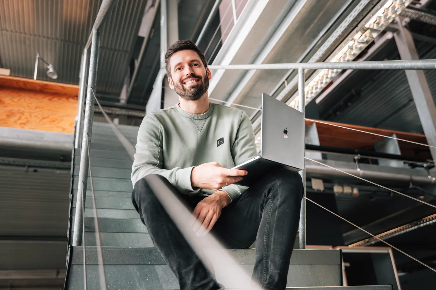 Mitglied Daniel sitzt mit Laptop auf der Treppe